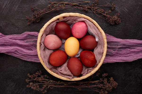 Easter composition with colored eggs on vintage dish, top view, flat lay. Naturally colored Easter eggs with wine, turmeric, onion peelings.