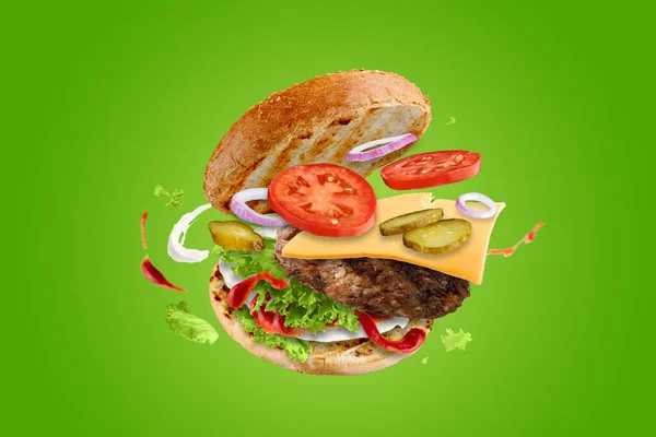 Velký chutný hamburger s létajícími prvky. Létající burger. Zelené pozadí. — Stock fotografie