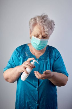Üst düzey kadın elleri yıkama jeli pompası kullanıyor, Yaşlı Asyalı kadın alkol dezenfektanı ile elini yıkıyor, virüsü ve bakterileri engelliyor, hijyen kavramı.