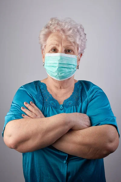 Old woman coronavirus helper. Old lady isolated at home. Home activities. Stay at home. Grandmother sewing face protection masks during quarantine. Old lady wearing protection mask. COVID-19 concept.