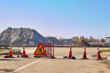 Yol çalışması işareti ve yol kenarındaki kırmızı koni..