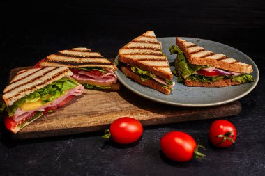 Tabakta dört sandviç. Koyu arkaplan.