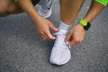 Sporcu erkek elleri koşu ayakkabılarına ayakkabı bağı bağlıyor