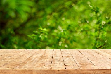 Yaprak bokeh arkaplanlı boş ahşap güverte masası.