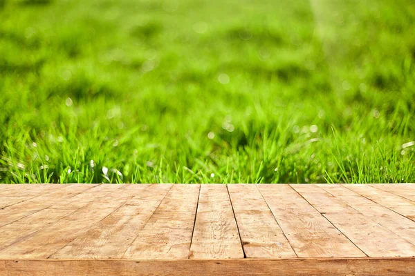 Boş ahşap güverte masası, yeşillik bokeh arka planlı. Ürün görüntüleme kurgusu için hazır.
