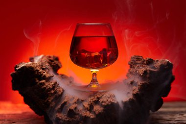 Tahta masada bir bardak viski, kırmızı renkli atmosfer, viskiyle dinlenme zamanı.