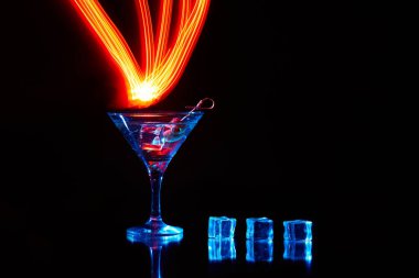 Uzun pozlu neon martini bardağı. Kırmızı kulüp ışıkları.