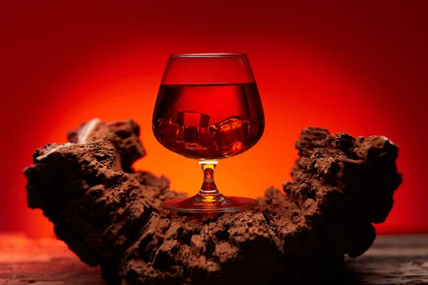 Tahta masada bir bardak viski, kırmızı renkli atmosfer, viskiyle dinlenme zamanı.