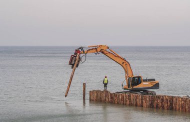 Özel bir teknik, dalgakıran için tahta kütükler hazırlar.