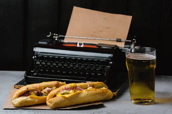 İki sosisli sandviç ve bira eski bir daktilo arka plan üzerinde.