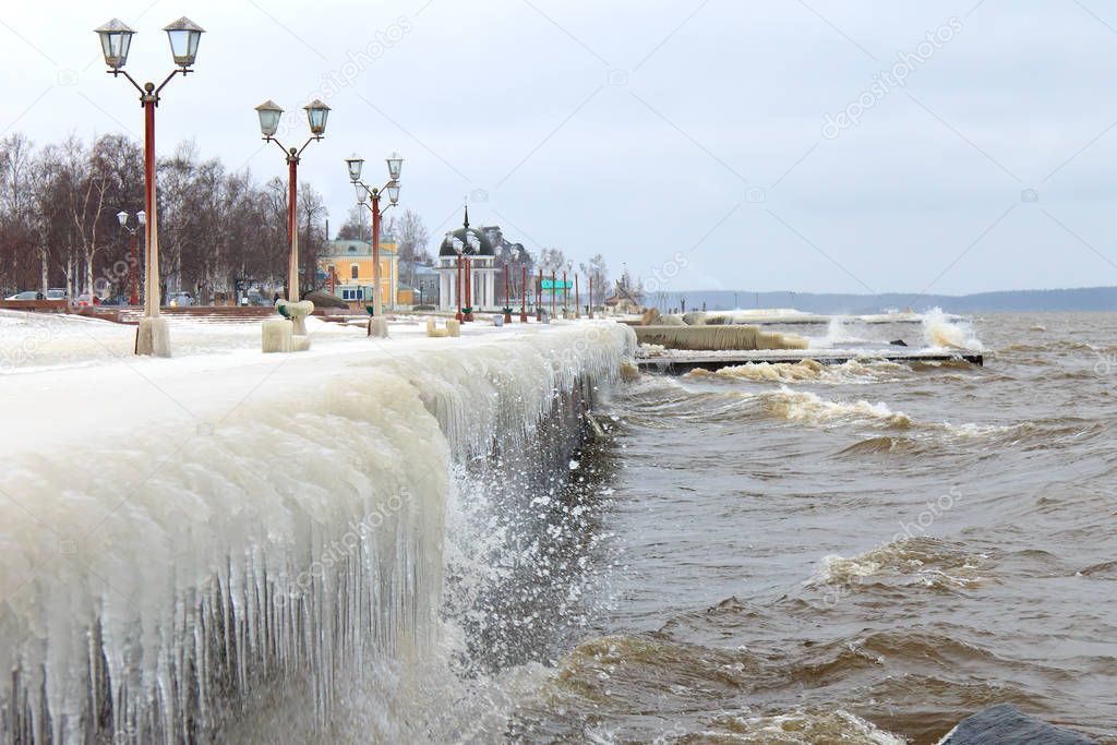 Winter storm on the lake and ice-covered city embankment
