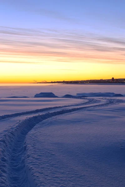Renkli ağarma gökyüzü altında kar arasında bir yol 