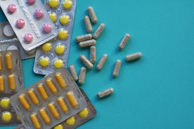 Bir kabarcık içinde çok renkli tabletler ve mavi arkaplan üzerinde kapsüller