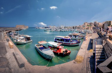 Iraklion, Girit, Yunanistan 'ın eski limanı. Mavi gökyüzü güneşli bir günde balıkçı tekneleri ve marinası var. Ön planda tekneler.