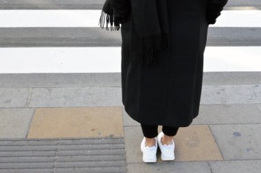 Low section of girl dressed in black and waiting at crossroad
