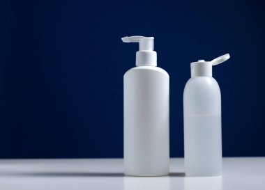 Mavi arkaplanlı plastik beyaz antiseptik şişesi..