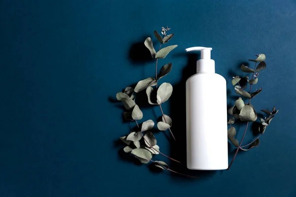 Plastic white bottle for antiseptic or gel with eucalyptus on a white table. Medical concept. Flat lay. Top topic 2020. Hygiene and antibacterial prevention. Industrial and home production.