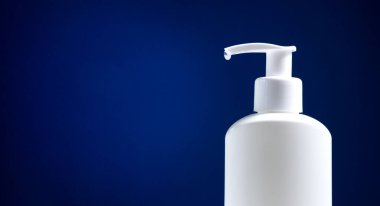 Koyu mavi arka planda beyaz dezenfektan şişesi. Virüs tasarımı konsepti. Minimalizm.