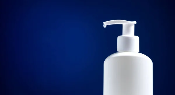 Koyu mavi arka planda beyaz dezenfektan şişesi. Virüs tasarımı konsepti. Minimalizm.