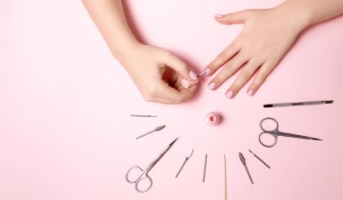 Genç kızın elleri bakımlı, tırnakları manikürlü. Manikür aletleri masaya yayılmış. Kız karantina sırasında kendi manikürünü yaptı. Evden çıkmak imkansızdı..