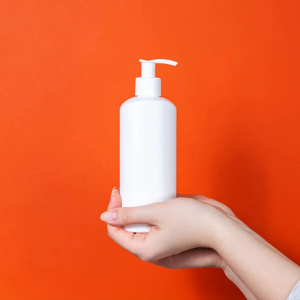 Turuncu arka planda plastik beyaz antiseptik şişesi..