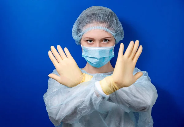 A young doctor in a medical uniform makes a forbidden gesture with his hands. — Stock Photo, Image