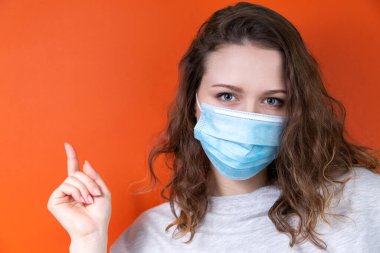 Tıbbi maskeli genç bir doktor bir posteri işaret ediyor..