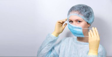 Tıp üniformalı genç ve yakışıklı bir doktor tıbbi maske takıyor..