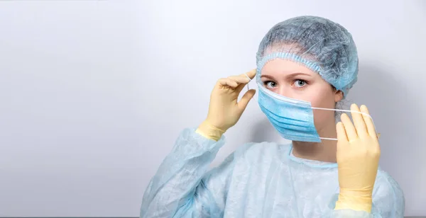 A young, handsome doctor in a medical uniform puts on a medical mask. — Stock Photo, Image