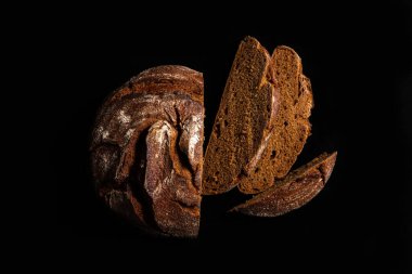 Siyah arka planda mayasız çavdar ekmeği. Üç dilim dilimlenmiş ekmek ve kırıntılar. Mesaj için yer. Bir tasarım projesi için pankart.