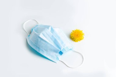 Tıbbi maske ve karahindiba beyaz bir masada yazmak için yeri olan. Tıbbi konsept. Bahar çiçekleri tasarım konseptine alerji.