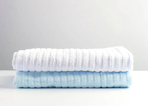 Белые и светло-голубые полотенца на белом столе . — стоковое фото