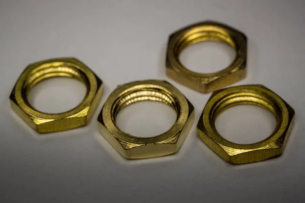 Macro de primer plano de cuatro tuercas de tornillo hexagonales de oro dispuestas aisladas sobre fondo blanco — Foto de Stock