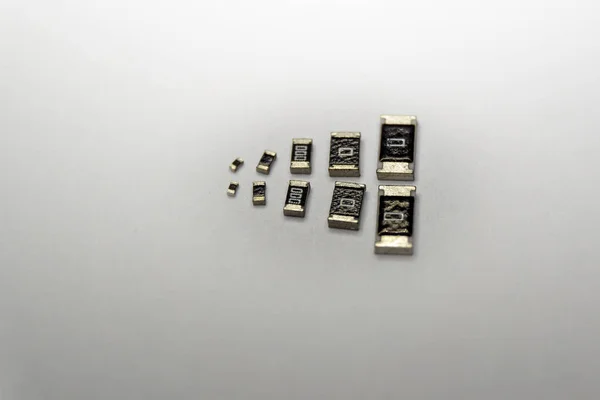 Primer plano abstracto de las resistencias dispersas de chips SMT de varios tamaños componentes electrónicos de potencia aislados sobre fondo blanco —  Fotos de Stock