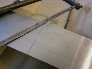 Paslı eski el testeresi, evdeki mobilya restorasyonu sırasında alüminyum plakayı kesiyor.