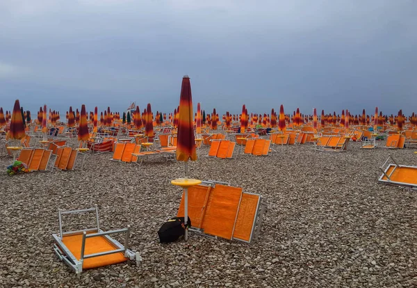 Orange umbrellas and chaise lounges on the beach of Fano in Ital