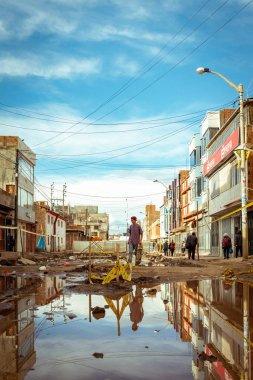 Desaguadero, Puno / Peru - 4 Nisan 2016: Büyük Kirli Su Çukuru ve Ürkütücü Tuğla Binaları olan Yırtık Ayrı Sokakta Kaykaylı Genç Adam
