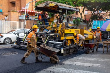 Medellin, Antioquia / Kolombiya - 19 Kasım 2019: Turuncu Üniformalı İnşaat İşçileri Bir Steamroller 'ın yanında bir el arabası kullanarak Sokakları Onarıyorlar