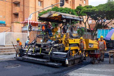 Medellin, Antioquia / Kolombiya - 19 Kasım 2019: Turuncu Üniformalı İnşaat İşçileri Bir Steamroller ile Sokakları Tamir Ediyor