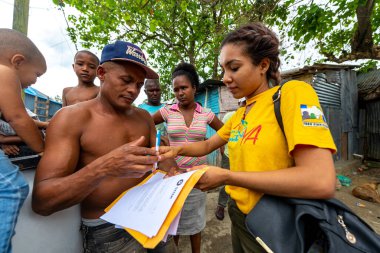 San Cristobal / Dominik Cumhuriyeti - 16 Mayıs 2018: Kahverengi Kadın, Çevresindeki Diğer İnsanlarla Üstsüz Kahverengi Adamın Önünde Bazı Kağıtları İmzalıyor