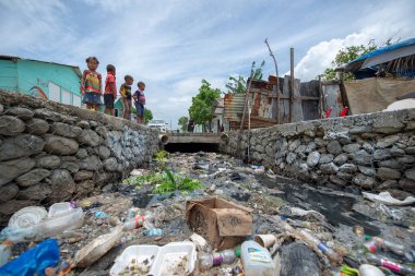 Santo Domingo / Dominik Cumhuriyeti - 16 Mayıs 2018: Los Guandules Mahallesi 'ndeki Ozama Nehri kıyısında çöp ve atıkla dolu su kemeri yakınında oynayan Chidren
