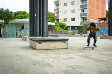 Medellin, Antioquia / Kolombiya - 10 Ekim 2019 - Uzun Kahverengi Saçlı İspanyol Adam Arka Tarafta Kaykay Yapıyor Smith Grind Trick