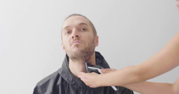 電気カミソリで白い白人の男の髭を剃るブルネットのラテン女性 — ストック動画