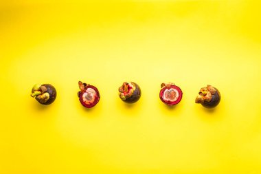 Üç Tüm Mangosteen (Garcinia Mangostana) Meyveler ve Bir Sarı Arkaplanda İkiye Bölünmüş