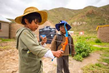 Poopo, Oruro / Bolivya - 14 Şubat 2018: Genç Yerli Uru Çocuk Oyuncak Yay ve Ok ile Başka Bir Çocuğun Yanında Oynuyor