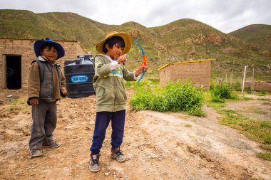 Poopo, Oruro / Bolivya - 14 Şubat 2018: Genç Yerli Uru Çocuk Oyuncak Yay ve Ok ile Başka Bir Çocuğun Yanında Oynuyor