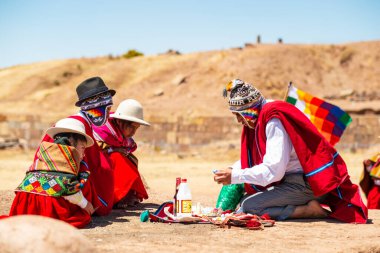 Tiwanaku, La Paz / Bolivya - 11 Eylül 2016: Geleneksel Wiphala Bayrağıyla Genç Yerli Aymara Adam Coca Leaves ile Coca Leaves İzleyen Çocuklar önünde Ayin Yapıyor