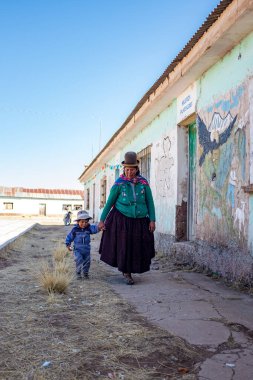 Jesus de Machaca, La Paz / Bolivya - 28 Temmuz 2016: Yerli Aymara Cholita Kadını ve Küçük Oğlu Elele Yürüyen Elle Köy Okul Duvarında Tabloları