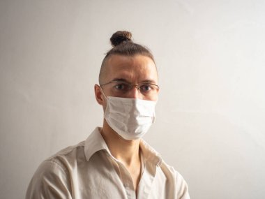 Beyaz tişörtlü, tek kullanımlık maske takan, Covid-19 için yakalanan, grip, virüs ve virüs kapmış beyaz saçlı beyaz erkek kameraya bakıyor.