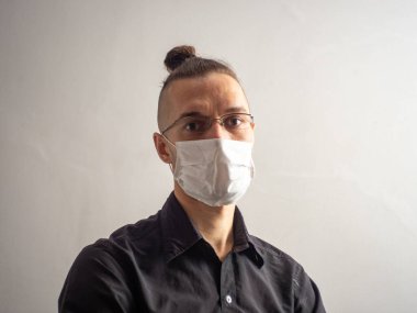 Siyah tişörtlü, tek kullanımlık yüz maskesi takan genç, sarı saçlı, beyaz erkek Covid-19 için yakalanan, grip, virüs, viral koruma.